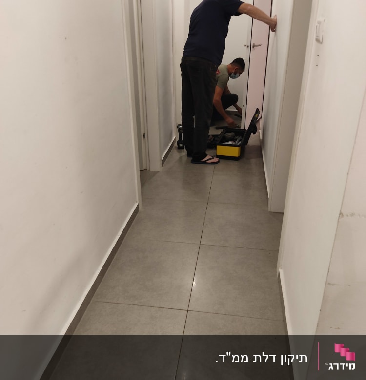 שני אנשים עובדים על דלת עם כלי עבודה